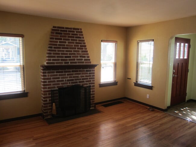 Sunny living room with wood-burning fireplace and hardwood floors - 7605 Robinson Way