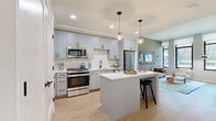 Located at 5 Port Imperial Blvd in Weehawken, NJ, this thoughtfully designed one-bedroom, one-bathroom residence offers a well-appointed open-concept layout finished with light hardwood flooring throughout. The kitchen is a standout feature, showcasing soft grey cabinetry with matte black hardware, a marble-style tile backsplash, white quartz countertops, stainless steel appliances, and a central island with pendant lighting — ideal for both everyday living and entertaining. The living room is bright and welcoming, with oversized black-framed windows that invite an abundance of natural light and frame views of the surrounding landscape. The bedroom continues the modern aesthetic with dual windows, blue-grey accent walls, and ample room for a full furniture arrangement. A dedicated walk-in closet offers custom built-in shelving and hanging storage, providing excellent organization. The bathroom is elegantly finished with large-format marble-look tile flooring, a warm wood vanity with white countertop, an LED-backlit mirror, and clean, neutral walls. Every detail of this residence reflects a cohesive, contemporary design sensibility suited for comfortable urban living in the Port Imperial waterfront community.