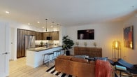 Located at 3425 W Olive Ave in Burbank, CA, this contemporary single-floor residence offers a thoughtfully designed open-concept layout with modern finishes throughout. The kitchen is a standout feature, outfitted with rich wood-grain cabinetry, stainless steel appliances including a French door refrigerator and gas range, a tile backsplash, and a breakfast bar with seating — all set atop light hardwood-style flooring. The kitchen flows seamlessly into the living area, which is bright and welcoming, featuring large windows that invite natural light and views of the surrounding neighborhood. The dining area offers a distinct design touch with a bold accent wall and track lighting, creating an intimate space for entertaining. Two bedrooms provide comfortable retreats; the primary bedroom includes a ceiling fan, plush carpeting, and access to a walk-in closet, while the secondary bedroom also features a walk-in closet and recessed lighting. The bathroom is elegantly finished with herringbone-patterned tile flooring, a dark wood vanity, an illuminated mirror, and a frameless glass-enclosed soaking tub and shower combo. A dedicated laundry area is also included within the unit, adding everyday convenience to this well-appointed Burbank residence.