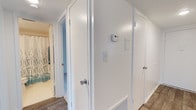 This upgraded 2-bedroom, 1-bathroom residence is thoughtfully laid out across a single floor, offering a comfortable and functional living environment. The interior features clean white walls, crisp white trim, and wood-look flooring that runs throughout, creating a cohesive and modern aesthetic. The hallway serves as a central hub connecting the key areas of the home, and is equipped with a thermostat and light switches for convenient climate and lighting control. Closet space is well incorporated into the layout, providing ample storage options. The bathroom, visible from the hallway, continues the bright, clean design theme with a shower-tub combination accented by decorative curtains. The textured ceilings add a subtle architectural detail found throughout the unit. The overall ambiance is bright, tidy, and move-in ready, reflecting the upgraded finishes that distinguish this residence. With a practical floor plan that maximizes every square foot, this home is well suited for those seeking a comfortable, low-maintenance living space with updated interior appointments.