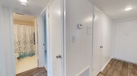This upgraded 2-bedroom, 1-bathroom residence is thoughtfully laid out across a single floor, offering a comfortable and functional living environment. The interior features clean white walls, crisp white trim, and wood-look flooring that runs throughout, creating a cohesive and modern aesthetic. The hallway serves as a central hub connecting the key areas of the home, and is equipped with a thermostat and light switches for convenient climate and lighting control. Closet space is well incorporated into the layout, providing ample storage options. The bathroom, visible from the hallway, continues the bright, clean design theme with a shower-tub combination accented by decorative curtains. The textured ceilings add a subtle architectural detail found throughout the unit. The overall ambiance is bright, tidy, and move-in ready, reflecting the upgraded finishes that distinguish this residence. With a practical floor plan that maximizes every square foot, this home is well suited for those seeking a comfortable, low-maintenance living space with updated interior appointments.