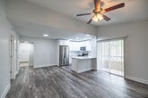 Located in Naples, FL, this single-floor, 3-bedroom, 3-bathroom home offers a bright and modern living experience with a clean, neutral aesthetic throughout. The open-concept layout connects the living room and kitchen seamlessly, with wood-look tile flooring and a ceiling fan adding warmth and comfort to the main living area. A sidelight window flanks the front door, allowing natural light to fill the entryway.

The kitchen is a standout feature, boasting crisp white shaker cabinetry, quartz countertops, a classic tile backsplash, and a full suite of stainless steel appliances including a refrigerator, electric range, and over-the-range microwave. A peninsula with an integrated sink provides additional prep space and casual seating. Vertical blinds along sliding glass doors offer access to the outdoors.

Each of the three bedrooms features wood-look tile flooring, ceiling fans, and generous closet space, including a walk-in closet in the primary bedroom. The three bathrooms are finished with white vanities, tile flooring, and glass-enclosed showers. A dedicated laundry room houses a full-size washer and dryer. The home's cohesive white-and-gray palette, recessed lighting, and functional layout make it a practical and comfortable residence in the heart of Naples.