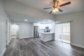 Located in Naples, FL, this single-floor, 3-bedroom, 3-bathroom home offers a bright and modern living experience with a clean, neutral aesthetic throughout. The open-concept layout connects the living room and kitchen seamlessly, with wood-look tile flooring and a ceiling fan adding warmth and comfort to the main living area. A sidelight window flanks the front door, allowing natural light to fill the entryway.

The kitchen is a standout feature, boasting crisp white shaker cabinetry, quartz countertops, a classic tile backsplash, and a full suite of stainless steel appliances including a refrigerator, electric range, and over-the-range microwave. A peninsula with an integrated sink provides additional prep space and casual seating. Vertical blinds along sliding glass doors offer access to the outdoors.

Each of the three bedrooms features wood-look tile flooring, ceiling fans, and generous closet space, including a walk-in closet in the primary bedroom. The three bathrooms are finished with white vanities, tile flooring, and glass-enclosed showers. A dedicated laundry room houses a full-size washer and dryer. The home's cohesive white-and-gray palette, recessed lighting, and functional layout make it a practical and comfortable residence in the heart of Naples.