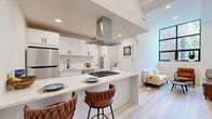 Located at 165 Richards St in West Haven, CT, this efficiently laid-out one-bedroom, one-bathroom unit offers a thoughtfully designed interior with modern finishes throughout. Light-toned hardwood-style flooring runs continuously across the space, enhancing its clean, contemporary aesthetic.

The kitchen is a standout feature, showcasing white shaker cabinetry with matte black hardware, quartz countertops, and a central island equipped with a gas cooktop and a stainless steel island range hood. The island doubles as a breakfast bar with seating, making it a functional hub. Stainless steel appliances, including a refrigerator and dishwasher, complete the well-appointed kitchen.

The living room benefits from tall, multi-pane windows that draw in natural light and offer views of the surrounding neighborhood, creating an airy and open atmosphere despite the compact footprint.

The bedroom is a serene retreat with crisp white walls, ample natural light, and a sliding door for privacy. The bathroom features neutral tile work, a full soaking tub with shower, a white vanity, and tile flooring, offering a clean and functional design.

Additional conveniences include an in-unit laundry area, rounding out this well-equipped, modern living space.