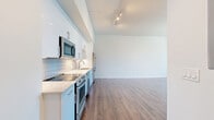 Located at 233 Kennedy St in the heart of Winnipeg, this modern one-bedroom, one-bathroom unit offers a thoughtfully designed open-concept layout with clean lines and contemporary finishes throughout. Warm wood-tone laminate flooring runs seamlessly across the entire space, complemented by crisp white walls and elevated ceilings with exposed structural elements that lend an urban, loft-inspired character. The kitchen is well-appointed with sleek white cabinetry extending to the ceiling, stone-look countertops, a subway tile backsplash, and a full suite of stainless steel appliances including a built-in microwave, range, dishwasher, and refrigerator. Track lighting illuminates the open kitchen and living area, which flows together to create a versatile and airy living space. The bedroom is a comfortable and private retreat, featuring large windows that frame impressive views of the Winnipeg cityscape and allow generous natural light to fill the room. The bathroom offers a refined finish with a soaker tub surrounded by bold marble-effect wall panels and chrome fixtures. In-unit laundry is also present, adding everyday convenience to this well-finished urban residence.