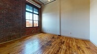 Located at 95 Chestnut St in the heart of Providence, Rhode Island, this loft-style unit blends industrial character with modern updates across a single floor. The living area is a standout, showcasing original hardwood floors with rich, warm tones, soaring ceilings with exposed ductwork, and a striking exposed brick wall. Large, multi-pane windows flood the space with natural light while framing views of the surrounding Providence cityscape, enhancing the open and airy atmosphere.

The kitchen is thoughtfully designed with white shaker cabinetry, dark granite-style countertops, and a full suite of stainless steel appliances, including an electric range, dishwasher, and refrigerator. An under-cabinet range hood and ample storage add both function and style, while the original hardwood floors continue seamlessly throughout.

A dedicated laundry closet houses a stacked washer and dryer unit, offering everyday convenience within the space. The bathroom features light tile flooring, a white vanity with a stone-tone countertop, a wall-mounted mirror with overhead lighting, and a tiled shower-tub combination. Clean, neutral finishes throughout maintain a cohesive and modern aesthetic that complements the building's historic industrial bones.
