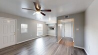 Located at 6009 Bellaire Blvd in Houston, TX, this single-story one-bedroom unit offers a practical and well-appointed layout across a comfortable footprint. The open-concept living room serves as the heart of the space, featuring durable hardwood-style flooring, neutral gray walls, and two windows that invite natural light. A ceiling fan overhead adds both function and comfort. The living area flows seamlessly into the kitchen, which is outfitted with white shaker-style cabinetry, granite-look countertops, a double stainless steel sink, and black appliances including a range and refrigerator. A pass-through window connects the kitchen to the living area, enhancing the open feel. The bedroom is generously sized, offering hardwood-style flooring, a ceiling fan, and a window with exterior views. It provides direct access to a walk-in closet featuring dual hanging rods and built-in shelving on both sides, offering ample storage. Throughout the unit, consistent flooring, clean white trim, and a cohesive neutral palette create a modern and move-in ready atmosphere. The single-floor layout ensures easy navigation and efficient use of every square foot.