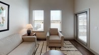 This thoughtfully designed single-floor unit blends modern aesthetics with everyday functionality. The open-concept kitchen is a standout feature, showcasing dark espresso cabinetry that extends to the ceiling, stainless steel appliances including a refrigerator, range, and over-the-range microwave, and a light granite-topped island with an integrated sink. A neutral tile backsplash and wood-look flooring complete the polished look. Pendant lighting and track lighting illuminate the space efficiently.

The living area is generously proportioned, benefiting from soaring ceilings and multiple windows fitted with horizontal blinds that allow for controlled natural light. The neutral color palette and warm wood flooring create a calm, welcoming ambiance throughout the main living space.

The bedroom offers a comfortable retreat with plush carpeting, a ceiling fan, and a window that provides natural light. The room comfortably accommodates a large bed and coordinating furnishings, maintaining the unit's clean, contemporary style.

The full bathroom is well-appointed with dark cabinetry, a granite vanity countertop, a single undermount sink, and a combined tub-shower unit. Wood-look flooring ties the bathroom seamlessly to the rest of the unit's design language, delivering a cohesive and modern finish throughout.