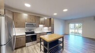 This well-appointed one-bedroom, one-bathroom residence in Menomonee Falls, WI offers a thoughtfully designed single-floor layout with modern finishes throughout. The open-concept kitchen is a standout feature, showcasing rich wood cabinetry, white subway tile backsplash, stainless steel appliances including a refrigerator, range, microwave, and dishwasher, along with light countertops and wood-look plank flooring that flows seamlessly into the living area. The living room is bright and airy, benefiting from natural light through a sliding glass door that opens to a private balcony with outdoor views. The bedroom offers plush carpeting, a ceiling fan, and a large window overlooking a natural backdrop, creating a calm and comfortable retreat. A dedicated walk-in closet with wire shelving provides generous storage. The bathroom features a full tub-shower combination, wood-look flooring, brushed nickel fixtures, and a vanity with dark wood cabinetry. A dedicated laundry room with a stacked full-size washer and dryer adds everyday convenience. Throughout the space, neutral tones and consistent finishes create a clean, cohesive aesthetic suited for comfortable living.