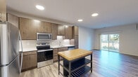 This well-appointed one-bedroom, one-bathroom residence in Menomonee Falls, WI offers a thoughtfully designed single-floor layout with modern finishes throughout. The open-concept kitchen is a standout feature, showcasing rich wood cabinetry, white subway tile backsplash, stainless steel appliances including a refrigerator, range, microwave, and dishwasher, along with light countertops and wood-look plank flooring that flows seamlessly into the living area. The living room is bright and airy, benefiting from natural light through a sliding glass door that opens to a private balcony with outdoor views. The bedroom offers plush carpeting, a ceiling fan, and a large window overlooking a natural backdrop, creating a calm and comfortable retreat. A dedicated walk-in closet with wire shelving provides generous storage. The bathroom features a full tub-shower combination, wood-look flooring, brushed nickel fixtures, and a vanity with dark wood cabinetry. A dedicated laundry room with a stacked full-size washer and dryer adds everyday convenience. Throughout the space, neutral tones and consistent finishes create a clean, cohesive aesthetic suited for comfortable living.