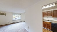 Located at 951 Perry Highway in Pittsburgh, PA, this single-floor residence offers a practical and comfortable layout across two bedrooms and one bathroom. The living room is a welcoming space featuring wall-to-wall carpeting, a large window that brings in natural light and outdoor views, a ceiling-mounted air conditioning unit, and baseboard heating. Crown molding adds a refined finishing touch to the space.

The kitchen is well-appointed with rich, warm-toned wood cabinetry, granite-style countertops, a stainless steel sink, and black appliances including an electric range with overhead ventilation. Adjacent hardwood-style flooring transitions smoothly from the kitchen into the hallway.

The spacious primary bedroom includes carpeted flooring, a ceiling fan with integrated lighting, a large window overlooking greenery, and baseboard heating. The second bedroom also features carpet, a window for natural light, and a closet with bifold louvered doors offering ample storage.

The bathroom is finished with white subway tile wainscoting, a granite-topped vanity with an undermount sink, a framed mirror, and wood cabinetry. A connecting hallway links all rooms efficiently, contributing to the space's cohesive, easy-to-navigate flow throughout.