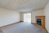 Located at 1608 Grandview Ave in Papillion, Nebraska, this two-bedroom, two-bathroom single-floor residence offers a well-organized layout across a comfortable footprint. The living room serves as a central gathering space, featuring plush carpeting, a textured ceiling, and a corner fireplace with a warm wood mantle. A sliding glass door floods the room with natural light and provides outdoor access. The open-concept kitchen and dining area features warm oak cabinetry, white appliances including a refrigerator, range, and microwave, and durable light-toned hardwood-style flooring that extends throughout the main living areas. Both bedrooms are carpeted and feature textured ceilings and windows that bring in natural light. The spacious primary bedroom offers generous room for furnishings. The two bathrooms are finished with oak vanities, solid-surface countertops, and mirrored medicine cabinets. A dedicated in-unit laundry room with overhead cabinetry accommodates a full-size washer and dryer. Three closets throughout the unit provide excellent storage capacity. Warm wood trim accents tie the interior together, creating a cohesive and comfortable living environment throughout.