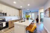Located at 4015 South Blvd in Charlotte, NC, this well-appointed 2-bedroom, 2-bathroom residence offers a thoughtfully designed single-floor layout with modern finishes throughout. The open-concept kitchen and living area serves as the heart of the home, anchored by a large waterfall-edge island with an undermount sink and seating for multiple guests. The kitchen features a two-tone cabinetry design — combining white upper cabinets with warm wood-toned lower cabinets — complemented by a clean white backsplash and stainless steel appliances. Light hardwood flooring flows throughout the main living areas, creating a bright and cohesive aesthetic. The living room is bathed in natural light from tall windows and French doors that open onto a private balcony, with a ceiling fan overhead adding comfort. Both bedrooms are carpeted and generously sized, with the primary bedroom offering walk-in closet access and abundant natural light from large windows. The bathrooms are finished with wood-look tile flooring, clean white tilework, glass-enclosed showers, and warm wood vanity accents with matte black fixtures. Additional highlights include two closets, a dedicated laundry area, and a utility room, rounding out this functional and stylish Charlotte residence.