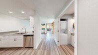 Located in Seattle's vibrant Wallingford neighborhood, Unit 102 at 4814 Interlake Ave N is a clean, modern single-floor residence featuring contemporary updates throughout. Light-toned luxury vinyl plank flooring runs continuously across the entire unit, lending a cohesive and polished feel to every room.

The galley-style kitchen is well-appointed with white shaker cabinetry, brushed hardware, quartz-style countertops, a stainless steel dishwasher, an electric range, and a full-size refrigerator — offering both style and functionality for everyday cooking.

A dedicated laundry closet houses a full stacked washer and dryer unit, providing the convenience of in-unit laundry. Adjacent to this is an additional utility or prep area with extra counter space.

The living area is bright and welcoming, with large windows and sliding glass doors that open directly to a private outdoor patio, allowing natural light to fill the space and providing a seamless indoor-outdoor connection to a landscaped exterior.

A standout architectural detail is the striking sliding partition door featuring a warm red-toned wood frame with frosted glass panels, offering a bold design accent while providing flexible room separation.

The bathroom is neatly finished with a single vanity, undermount sink, quartz countertop, a tub-shower combination, and wood-look flooring that ties in with the rest of the unit.