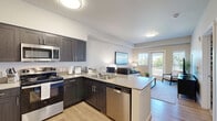 Located at 2575 NE Mary Rose Pl in Bend, Oregon, this well-designed one-bedroom, one-bathroom residence offers a smart and functional layout across a single floor. The open-concept living area seamlessly connects the kitchen, dining, and living spaces, creating an efficient yet comfortable flow.

The kitchen is a standout feature, outfitted with dark espresso cabinetry, light quartz-style countertops, and a full suite of stainless steel appliances including a refrigerator, range, microwave, and dishwasher. A peninsula with bar seating adds both prep space and a casual dining option. Light wood-look flooring runs throughout the main living areas, enhancing the bright, neutral palette.

The living room is inviting and well-lit, benefiting from natural light and direct access to a private balcony with outdoor views. The bedroom is a comfortable retreat featuring plush carpet, a ceiling fan, and a window that brings in additional natural light, complemented by two closets for generous storage.

The bathroom is elongated and thoughtfully appointed with dark wood cabinetry, a wide vanity with a large mirror, and a shower-tub combination. A dedicated laundry area adds everyday convenience. The overall aesthetic is clean, modern, and cohesive throughout.