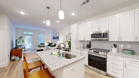 Located at 1850 Benton Blvd in Savannah, GA, this thoughtfully designed one-bedroom, one-bathroom residence offers a functional and modern single-floor layout. The open-concept living and kitchen area serves as the heart of the home, where light hardwood-style flooring flows throughout, enhancing the bright, airy atmosphere created by crisp white walls and recessed lighting.

The kitchen is a standout feature, outfitted with white shaker-style cabinetry, a subway tile backsplash, stainless steel appliances including a range, microwave, and French door refrigerator, and a granite-topped island with an undermount sink and pendant lighting above. The island provides additional seating, making it ideal for casual dining.

The living room benefits from a large sliding glass door and windows that invite natural light and offer views of the surrounding greenery, creating a comfortable and welcoming atmosphere.

The bedroom features plush carpeting, a ceiling fan, and a generously sized window that further brightens the space. A dedicated closet provides practical storage. The bathroom mirrors the kitchen's design language with white cabinetry, granite countertops, a framed mirror, and light hardwood-style flooring, maintaining a cohesive aesthetic throughout the residence.