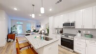 Located at 1850 Benton Blvd in Savannah, GA, this thoughtfully designed one-bedroom, one-bathroom residence offers a functional and modern single-floor layout. The open-concept living and kitchen area serves as the heart of the home, where light hardwood-style flooring flows throughout, enhancing the bright, airy atmosphere created by crisp white walls and recessed lighting.

The kitchen is a standout feature, outfitted with white shaker-style cabinetry, a subway tile backsplash, stainless steel appliances including a range, microwave, and French door refrigerator, and a granite-topped island with an undermount sink and pendant lighting above. The island provides additional seating, making it ideal for casual dining.

The living room benefits from a large sliding glass door and windows that invite natural light and offer views of the surrounding greenery, creating a comfortable and welcoming atmosphere.

The bedroom features plush carpeting, a ceiling fan, and a generously sized window that further brightens the space. A dedicated closet provides practical storage. The bathroom mirrors the kitchen's design language with white cabinetry, granite countertops, a framed mirror, and light hardwood-style flooring, maintaining a cohesive aesthetic throughout the residence.