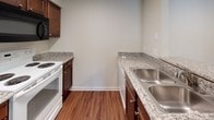 Located at 1878 E 9 Mile Rd in Pensacola, Florida, this single-floor residence offers a well-organized layout designed for comfortable everyday living. The living room serves as the heart of the home, highlighted by a tile-surround fireplace, a ceiling fan with light fixture, and a sliding glass door that invites natural light and provides access to an outdoor area with greenery views. Wood-look flooring flows through the entry and kitchen areas, while plush carpet covers the living and bedroom spaces.

The kitchen is thoughtfully appointed with rich dark wood cabinetry, granite-patterned countertops, a double stainless steel sink, and a full suite of appliances including a refrigerator, electric range, and built-in microwave. A peninsula counter connects the kitchen to the living area, creating an open and functional flow.

The bedrooms are generously sized, each featuring ceiling fans, natural window light, and ample closet space — including both louvered double-door closets and a walk-in closet with wire shelving. The bathrooms echo the kitchen's design aesthetic with matching dark wood vanities, granite-patterned countertops, brushed nickel fixtures, and large mirrors. One bathroom includes a full tub and shower combination with wood-look flooring, completing this well-appointed Pensacola residence.