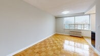 Located on the fifth floor at 65 Windermere Avenue in Toronto's Swansea neighbourhood, this studio unit offers a well-organized layout across a single floor. The combined living and dining area is the heart of the suite, featuring warm parquet wood flooring laid in a classic basket-weave pattern and neutral grey walls that create a clean, versatile backdrop. A large window allows natural light to fill the space while offering an outdoor view, and a radiator beneath the window provides efficient heating. Two entrance points and two closets add practical storage and circulation options.

The kitchen is a separate, efficiently designed space outfitted with white upper and lower cabinetry, granite-style countertops, a stainless steel refrigerator, a stove, and a sink — all set on light ceramic tile flooring. The layout makes effective use of the available footprint, providing ample storage and workspace for everyday cooking.

The bathroom is finished in a crisp all-white palette with ceramic tile flooring, a pedestal-style vanity with a mirrored medicine cabinet, a toilet, and a bathtub, all illuminated by a wall-mounted light fixture above the mirror. The overall ambiance of the unit is bright, functional, and well-maintained, making it a practical urban residence in a well-connected Toronto neighbourhood.