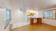 This 390 square foot apartment in Boulder, Colorado, offers a thoughtful design that maximizes space efficiency. The single-story layout comprises one bedroom, one bathroom, and a well-equipped kitchen. The bedroom, measuring 110 square feet, features a large window allowing ample natural light and a spacious closet with sliding doors for storage.

The kitchen is a highlight, boasting modern appliances including a refrigerator, stove, and built-in microwave. Light wood cabinetry contrasts nicely with the white appliances and walls. A granite countertop extends to form a breakfast bar, creating a functional divide between the kitchen and living area.

The bathroom, though compact, includes a shower with a textured glass door for privacy. Throughout the apartment, the flooring alternates between warm hardwood in the main living areas and practical tile in the kitchen and bathroom. Track lighting in the kitchen adds a contemporary touch, while the living area and bedroom feature carpeting for comfort.

Despite its modest size, the apartment's layout creates distinct spaces for living, sleeping, and dining. The neutral color palette and abundance of natural light contribute to an open, airy feel, making the space appear larger than its actual square footage suggests.