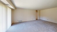 Located at 2000 Veterans Hwy in Levittown, PA, this single-floor unit offers a well-organized layout designed for comfortable, everyday living. The open living and dining area is finished with plush wall-to-wall carpeting and neutral cream-toned walls, creating a clean, airy atmosphere. Large vertical blinds and windows along the exterior wall allow abundant natural light to fill the space while providing views of the surrounding area. A pendant light fixture marks the dining zone, adding a subtle design touch.

The kitchen features warm wood cabinetry, dark granite-style countertops, and hardwood-style flooring, lending a grounded, functional character to the cooking space. It connects seamlessly to the rest of the unit via a central hallway.

The bedrooms are generously proportioned, each carpeted and well-lit by natural light from windows. Sliding and bifold closet doors provide ample built-in storage, and one bedroom includes a dedicated walk-in closet area. The neutral palette throughout keeps the rooms feeling open and versatile.

The bathroom is clean and efficiently laid out, featuring a full tub and shower combination with tiled surround, hardwood-style flooring, and accessibility grab bars along the walls. Overall, the unit presents a practical and comfortable living environment in a convenient Levittown location.