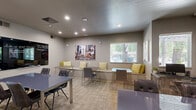 Located at 1659 Drew Ave in Davis, California, this dining room is a thoughtfully designed communal space that balances functionality with contemporary style. The room is finished with neutral gray walls and textured carpeting in a warm grid pattern, creating a clean and inviting atmosphere throughout.

Multiple seating configurations accommodate a variety of uses. A central rectangular table with upholstered dark leather chairs serves as the primary gathering point, while a built-in bench along one wall is lined with yellow and green accent pillows, paired with compact bistro-style tables and sleek metal chairs. An additional table and chair set near the window furthers the room's flexibility for both dining and informal meetings.

Recessed lighting installed across the ceiling provides consistent, even illumination, supplemented by natural light filtering through slatted window blinds. The space is further enlivened by a collection of bold, large-format artwork adorning the walls, including a vivid cityscape print and colorful abstract pieces that add a dynamic, urban character to the room.

A wall-mounted television and chalkboard panel enhance the room's utility for presentations or group activities. French doors with glass panels connect the space to an adjacent area, contributing to an open and accessible flow. Overall, the room offers a modern, multifunctional environment well-suited for dining, socializing, or collaborative gatherings.