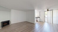 Located in the heart of Hollywood at 1321 N Las Palmas Ave, this 2-bedroom, 1-bathroom residence offers a clean, modern aesthetic throughout its single-floor layout. Light wood-style flooring runs continuously through every room, creating a cohesive and airy feel. The open living area is bright and inviting, anchored by a fireplace and sliding glass doors that lead to an outdoor space, filling the room with natural light. A ceiling fan adds functional comfort to the living space. The galley-style kitchen is well-appointed with white shaker cabinetry, dark countertops, stainless steel appliances including a gas range and dishwasher, and a window that brings in additional natural light. A central hallway connects the bedrooms and bathroom, maintaining a logical and efficient flow. The primary bedroom is generously sized, featuring a window with greenery views, while the second bedroom includes mirrored sliding closet doors. The shared bathroom is cleanly finished with white cabinetry, a single-sink vanity with a large mirror, and a shower-tub combination with white tile surround. Throughout, the crisp white walls and consistent finishes create a bright, move-in ready environment in a prime Los Angeles location.