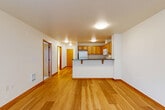 Located in Seattle's vibrant Greenwood neighborhood, this well-appointed one-bedroom, one-bathroom unit offers a thoughtfully designed layout across a single floor. The open-concept living area seamlessly connects the living room, dining space, and kitchen, all finished with warm hardwood-style flooring and clean white walls that create a bright, welcoming atmosphere. The kitchen is well-equipped with honey-toned wood cabinetry, dark granite-style countertops, a peninsula with bar seating, and a full suite of white appliances including a refrigerator, range, microwave, and dishwasher. A hallway leads to the private bedroom, which features plush carpet, a large window overlooking the balcony, and mirrored sliding closet doors. The unit is further complemented by three closets, offering generous storage throughout. The full bathroom includes a vanity with wood cabinetry, a tub-shower combo, and hardwood-style flooring. A dedicated in-unit laundry room houses a full-size washer and dryer. The private balcony provides an outdoor retreat, rounding out a functional and comfortable living space in one of Seattle's most walkable communities.