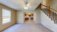 Located at 1006 E Wildcat Run St in Gardner, Kansas, this two-story home is designed with a practical, straightforward layout that flows naturally between living spaces. The main level welcomes residents through a tiled entryway framed by a striking staircase with warm wood handrails, white balusters, and vaulted ceiling height that lends an open, airy feel to the foyer. Plush carpeting extends through the living area, which connects openly to the kitchen via a wide pass-through opening. The kitchen features warm honey-toned oak cabinetry arranged in an L-shape, offering generous storage and counter space. A white range, built-in microwave, and dishwasher are included, and light tile flooring ties the space together. A ceiling fan with integrated lighting fixture serves the living area.

The bathrooms include a full tub/shower combo with clean white surround and tile flooring, as well as a separate shower enclosure with sliding glass doors. Upstairs, the carpeted bedrooms offer neutral tones and natural light through standard windows. The attached garage provides ample room for vehicles, equipped with an automatic opener, and features a textured ceiling and concrete flooring.