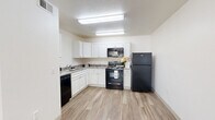 Located at 2455 N Dodge Blvd in Tucson, Arizona, this single-story, three-bedroom, one-bathroom home offers a practical and comfortable layout. Wood-look luxury vinyl flooring runs throughout the entire home, providing a cohesive and easy-to-maintain finish. The combined kitchen and living room forms the heart of the home, with the kitchen featuring white cabinetry, light stone-look countertops, and a full suite of black appliances including a refrigerator, range, microwave, and dishwasher. The living room area is bright and open, accessed through a classic six-panel entry door. A connecting hallway leads to all three bedrooms and the shared bathroom. Each bedroom is finished with the same wood-look flooring, ceiling fans with integrated lighting, and windows fitted with vertical blinds that allow natural light while maintaining privacy. Built-in closets provide dedicated storage in the bedrooms. The shared bathroom includes a shower-tub combination. Clean white walls and neutral tones throughout create a bright, move-in-ready atmosphere well-suited to the sunny Tucson climate.