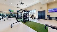 Located at 3811 Commerce Way in Sacramento, CA, this fitness center offers a generously sized, single-floor exercise room designed to support a full range of workout routines. The space features soaring ceilings that create an open, airy atmosphere, complemented by expansive floor-to-ceiling windows along the perimeter that flood the interior with natural light and provide views of the surrounding exterior. Ceiling fans and recessed lighting add to the comfort and functionality of the environment.

The exercise area is thoughtfully organized into distinct workout zones. A turf-lined functional training area runs through the center of the room, anchored by a multi-station rig stocked with kettlebells, medicine balls, and battle ropes. An extensive free weight section offers a full dumbbell rack alongside adjustable benches, while a variety of strength machines line the walls. Cardio equipment, including stair climbers, stationary bikes, and treadmills, is positioned near the windows to take advantage of the natural light and outdoor views.

Full-length mirrors along one wall enhance the sense of space and support form monitoring during workouts. Multiple wall-mounted flat-screen televisions are positioned throughout the room. The entry area features a clean, welcoming vestibule with a wall-mounted display, a beverage cooler, and a device-charging station, providing a polished and convenient arrival experience.