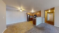 Located at 2554 Airport Rd in Portage, Wisconsin, this single-floor unit offers a practical and well-appointed layout designed for comfortable everyday living. The open-concept living and kitchen area forms the heart of the unit, where tile flooring transitions seamlessly into plush carpeting in the living space. A ceiling fan overhead provides year-round comfort in the living area. The kitchen is equipped with warm medium-toned wood cabinetry, granite-style countertops, and a full suite of stainless steel appliances including a refrigerator, range, and over-the-range microwave. A peninsula with a breakfast bar adds both prep space and a casual dining option, while maintaining the open flow between kitchen and living areas. The bedrooms are generously sized, each featuring soft carpet, ceiling fans, natural light from windows, and baseboard heating. The unit includes two bathrooms — one with a granite-topped vanity and a walk-in shower stall, and another full bathroom with matching finishes and additional cabinetry for storage. A dedicated laundry room with tile flooring and ample wire shelving adds convenience and extra storage capacity. Overall, the unit presents a clean, functional aesthetic with consistent finishes throughout.