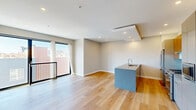 Located at 517 Poplar St in Philadelphia's vibrant Northern Liberties neighborhood, this contemporary one-bedroom, one-bathroom unit offers a well-designed single-floor layout with high-end finishes throughout. Light hardwood flooring runs seamlessly across all rooms, complementing the neutral color palette and recessed lighting that give the space a clean, modern aesthetic.

The open-concept kitchen and living area serves as the heart of the unit. The kitchen features a striking island with a stone countertop and integrated sink, a mix of walnut and matte cabinetry, a subway tile backsplash, stainless steel appliances including a gas range and refrigerator, and a built-in microwave. A coffered ceiling detail above the kitchen adds architectural interest. The living area is bathed in natural light from large floor-to-ceiling windows that open to a private balcony, offering elevated views of the Philadelphia skyline and surrounding neighborhood.

A clean, well-lit hallway connects the living spaces to the private quarters, featuring two closets for ample storage. The bedroom is comfortably sized with a large window framing expansive city views and includes additional closet space. The bathroom is appointed with elegant floor-to-ceiling linear tile in the walk-in glass shower, penny mosaic tile flooring, and polished chrome fixtures, delivering a spa-like experience.