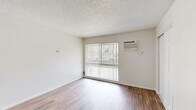 Located at 3902 Annadale Ln in the Arden-Arcade neighborhood of Sacramento, CA, this one-bedroom, one-bathroom unit offers a compact and functional layout across a single floor. The living room is a bright, open space featuring wood-style laminate flooring, a textured ceiling, and a large sliding glass door dressed with vertical blinds that invites abundant natural light and provides outdoor views. A wall-mounted air conditioning unit ensures year-round comfort, while a ceiling fan in the adjacent entry area adds to the airflow and ambiance. The kitchen area connects conveniently to the main living space, as seen in the floor plan layout. The bedroom is a well-proportioned, quiet retreat finished with plush carpeting, a textured ceiling, and a window with vertical blinds that provides natural light. A set of double sliding closet doors offers practical storage. The full bathroom is cleanly appointed with wood-style flooring, a warm-toned vanity with storage, a wall-mounted mirror, and a shower-tub combination with a curtain rod. Throughout the unit, neutral white walls and clean finishes create a bright, move-in-ready atmosphere suited for comfortable everyday living.