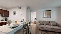 This single-story, one-bedroom, one-bathroom unit in Spartanburg, SC offers a well-organized layout that makes efficient use of its space. The living room serves as the heart of the unit, featuring durable hardwood-style flooring, neutral walls, and multiple windows fitted with blinds that allow generous natural light to fill the room. The open sightlines create a welcoming, airy atmosphere suited for both relaxing and entertaining.

The kitchen is equipped with rich, dark cabinetry, a classic white subway tile backsplash, a black electric range, and light countertops that provide ample workspace. A small breakfast bar with seating connects the kitchen to the dining area, optimizing the use of available space and encouraging a casual dining setup.

The bedroom offers a comfortable, carpeted retreat with a ceiling fan, a window with outdoor views, and enough space to accommodate standard furnishings including a bed, dresser, and nightstands. The neutral color palette throughout keeps the room calm and versatile.

The bathroom features a clean, modern design with white cabinetry, a light-toned countertop vanity with a large mirror, and a full shower-tub combination. Hardwood-style flooring extends into the bathroom, maintaining a consistent aesthetic throughout the unit.
