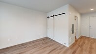 Located at 513 1st Ave N in Seattle's Lower Queen Anne neighborhood, this efficiently designed studio offers a thoughtful single-floor layout that maximizes every square foot. Light wood-style flooring flows throughout, creating a cohesive and clean aesthetic across all areas.

The combined kitchen and living area serves as the heart of the unit, anchored by a full suite of stainless steel appliances, including a refrigerator, dishwasher, electric range, and over-the-range microwave. The kitchen features two-tone cabinetry — natural wood-finish upper cabinets paired with dark lower cabinets — complemented by a light countertop and a subway tile backsplash. A striking floor-to-ceiling window wall floods the space with natural light and provides open city views, giving the living area an airy, expansive feel.

A stylish barn door with a matte black rail system opens to a dedicated closet space, adding a modern design detail while conserving floor space. The bathroom and laundry combination is finished with matte black fixtures, a full soaking tub and shower, and a stone-topped vanity, offering a clean, contemporary aesthetic. Recessed lighting throughout the unit ensures consistent, well-distributed illumination. This studio presents a modern and functional urban living space in the heart of Seattle.