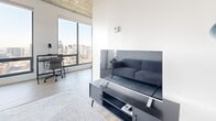 Located on Boulevard René-Lévesque Ouest in the heart of downtown Montréal, this one-bedroom, one-bathroom unit offers a contemporary urban living experience defined by clean lines and industrial-modern design. The layout includes a living room, bedroom, hallway, and bathroom, all finished with light hardwood-style flooring and crisp white walls that maximize the sense of brightness throughout.

The living room is a comfortable and well-proportioned space, anchored by large floor-to-ceiling windows that frame sweeping views of the Montréal skyline. Exposed concrete columns and ceilings add a striking industrial character that contrasts beautifully with the otherwise minimal, light-filled interior.

The bedroom benefits from dual floor-to-ceiling windows on two walls, filling the room with natural light while offering panoramic city views. The exposed concrete ceiling continues here, reinforcing the cohesive architectural aesthetic throughout the unit.

A hallway connects the main living areas and leads to the full bathroom, which features classic white square tile walls and warm beige floor tiles. The bathroom is equipped with a glass-enclosed shower, a wall-mounted white vanity, and a toilet, offering a clean and functional layout.

This high-floor unit's abundant natural light, dramatic city views, and distinctive exposed concrete finishes make it a standout urban residence in one of Montréal's most vibrant neighborhoods.