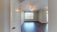 This single-story residence offers a well-organized layout with a variety of thoughtfully designed living spaces. The main living area features dark hardwood-style flooring, crown molding along the ceiling, and a ceiling fan with light fixture, creating a polished and comfortable atmosphere. A large window floods the room with natural light and provides views of the surrounding greenery, while an adjacent dining area benefits from a pendant light fixture and access to additional natural light through glass doors.

The kitchen is outfitted with warm oak cabinetry offering generous storage, granite-style countertops, and a full suite of white appliances including a range, over-the-range microwave, dishwasher, and refrigerator. Dark hardwood-style flooring continues throughout the kitchen, lending visual continuity.

Multiple bedrooms are carpeted and feature neutral tones, ceiling fans, and windows with blinds that frame outdoor views. Each room provides a calm, versatile space suitable for various uses.

The bathrooms include warm wood vanity cabinetry with granite-style countertops, hardwood-style flooring, and a tub-shower combination with white tile surround. The overall ambiance of the residence is clean, neutral, and move-in ready.