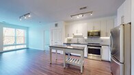 Located at 11500 Commerce Park Dr in Reston, Virginia, this single-floor residence offers a thoughtfully designed layout with modern finishes throughout. The open-concept kitchen is a standout feature, boasting crisp white cabinetry with under-cabinet lighting, a classic subway tile backsplash, dark granite countertops, and a full suite of stainless steel appliances including a range, microwave, refrigerator, and dishwasher. Track lighting illuminates the space, which flows seamlessly onto durable hardwood-style flooring that extends through the living and dining areas. The living area provides generous open space with a built-in desk nook, adding functional versatility. Bedrooms are finished with plush carpeting and feature windows with blinds that invite natural light and offer views of the surrounding landscape. The primary bathroom includes a double-sink vanity with wood-toned cabinetry, stone-look countertops, large-format white tile flooring, and a soaking tub with a tiled surround. A second full bathroom mirrors the clean, modern aesthetic with tiled tub-shower combo and wood-accented storage. The overall ambiance is bright, clean, and contemporary, making this Reston residence a well-appointed and functional living space.