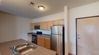 This single-story unit is designed with a practical, open layout that connects the living and kitchen areas seamlessly. The kitchen serves as a functional centerpiece, featuring light maple cabinetry with ample upper and lower storage, dark countertops, and a full suite of stainless steel appliances including a refrigerator, range, and over-the-range microwave. A peninsula with a built-in sink and pendant lighting above provides additional workspace and a natural division between the kitchen and the carpeted living area. An entry closet near the front door offers convenient storage upon arrival.

The living space is generously sized with soft carpeting underfoot, vaulted ceilings in select areas, and access to a sliding glass door that brings in natural light. Bedrooms are comfortably scaled, carpeted, and include windows with exterior views. The unit includes multiple bathrooms, each with wood-look vinyl flooring, vanities with storage, and either a soaking tub or walk-in shower. One bathroom also features direct access to a walk-in closet with built-in shelving. Throughout the unit, neutral wall tones and wood-trimmed baseboards contribute to a clean, cohesive aesthetic.