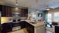 Located at 2301 E 10th St in Greenville, NC, this single-floor residence offers a cohesive and well-designed living environment with modern finishes throughout. The kitchen is a standout feature, boasting rich dark-espresso cabinetry, granite countertops, a peninsula with an undermount sink, and a full suite of stainless steel appliances including a refrigerator, electric range, microwave, and dishwasher. Track lighting and stylish pendant lights illuminate the space, which flows seamlessly into the living area. The living room is bright and inviting, featuring wood-look flooring, a ceiling fan, large windows with outdoor access, and ample natural light. The bedrooms offer comfortable retreats, each with wood-look flooring, ceiling fans, natural light from windows, and generous space. The bathrooms maintain the home's consistent design language, featuring dark cabinetry with granite countertops, undermount sinks, wall-mounted storage cabinets, and shower/tub combinations. Wood-look flooring carries through the bathrooms as well. An in-unit laundry area is also present, adding everyday convenience. Neutral gray wall tones and quality finishes create a unified, modern aesthetic throughout the entire residence.