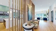 Located at 112 Point Place in Mooresville, NC, this single-story community clubhouse offers a generously sized, open-concept layout designed for socializing and recreation. The entrance hallway immediately impresses with soaring double-height ceilings, warm wood detailing, sleek black-framed glass partitions, and a statement chandelier, setting an upscale tone throughout.

The main gathering area is a versatile, light-filled space featuring wide-plank hardwood flooring and large floor-to-ceiling windows that flood the interior with natural light and provide views of the outdoor pool area. A stylish lounge zone anchors one end, furnished with bold cobalt-blue channel-tufted sofas, a card or game table with green upholstered chairs, and a wall of arched built-in shelving framing a mounted television and fireplace. A gold globe chandelier adds an elegant finishing touch overhead.

The game room area showcases a professional blue-felt billiards table beneath a striking teal-paneled ceiling detail and a modern multi-globe pendant light. A slatted wood room divider elegantly separates zones without closing off the open flow. A wet bar with teal tile backsplash, pendant lighting, and counter seating provides an ideal entertaining hub. The cohesive blue, teal, and gold color palette ties the entire space together with a sophisticated, resort-inspired aesthetic.