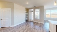 Located at 15101 Royal Creek Dr in Fuquay-Varina, NC, this 2-bedroom, 2-bathroom residence offers a clean, modern aesthetic with a practical and comfortable layout. The open-concept living, dining, and kitchen area serves as the heart of the home, featuring wood-look plank flooring, recessed lighting, and abundant natural light from multiple windows. The kitchen stands out with dark cabinetry, stainless steel appliances, a large center island with a white countertop and built-in sink, and stylish pendant lighting. The living area includes built-in shelving and direct access to a private balcony. Both bedrooms are carpeted and include ceiling fans, natural light from windows with exterior views, and generous closet space. The primary bedroom is notably spacious and is supported by five closets throughout the unit, including a walk-in closet with wire shelving systems. The bathrooms feature wood-look flooring and a tub-shower combination with classic white subway tile and brushed nickel fixtures. A well-lit hallway connects the spaces seamlessly, while a dedicated in-unit laundry room with washer and dryer hookups and wire shelving adds everyday convenience to this well-designed home.