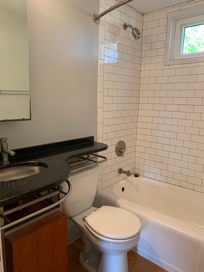 Updated bath with granite countertops, subway tile shower, and custom storage. - 631 Daniels St