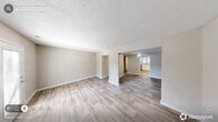 This two-story home in Durham, NC offers a thoughtfully designed layout spread across two floors. The main level features a bright living room with light wood-look flooring, neutral gray walls, and a textured ceiling, creating a clean and welcoming atmosphere. Natural light filters in through exterior-facing windows and a glass door, enhancing the open feel of the space. The kitchen is a standout feature, showcasing crisp white shaker-style cabinetry, a mosaic tile backsplash, stainless steel appliances including a refrigerator, electric range, microwave, and dishwasher, and generous counter space beneath a skylight window that fills the room with daylight. A hallway with a staircase featuring rich dark wood treads and a white balustrade connects both floors, adding a classic touch to the interior. Upstairs, the two carpeted bedrooms offer a comfortable retreat. The primary bedroom includes a mirrored sliding-door closet and dual windows that bring in ample natural light. Each bathroom is finished with white vanity cabinetry and a tub-shower combination. Throughout the home, consistent neutral tones and updated finishes create a cohesive, move-in-ready environment.
