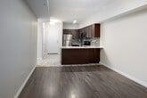 Located on the fourth floor at 5 Rittenhouse Rd in Kitchener, Ontario, this well-appointed one-bedroom, one-bathroom unit offers a thoughtfully designed layout across a single floor. The open-concept kitchen and living area forms the heart of the unit, bathed in natural light from a large window and a glass balcony door that leads to a private outdoor space. The kitchen is fitted with rich dark-wood cabinetry, granite countertops, a mosaic tile backsplash, and a full suite of stainless steel appliances including a refrigerator, electric range, and built-in microwave. Track lighting overhead adds a modern touch. The living area features durable hardwood-style laminate flooring that flows seamlessly throughout. The bedroom is a cozy, well-proportioned retreat with double closet doors offering ample storage, complemented by tile flooring. The four-piece bathroom is finished with a granite-topped vanity with a wood cabinet, a combined tub and shower, and neutral tile flooring, maintaining the consistent quality found throughout the unit. Warm, neutral tones across all rooms create a clean and welcoming ambiance, making this a practical and comfortable space in a residential Kitchener neighbourhood.