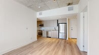 Located at 770 Somerset St W in Ottawa's vibrant Centretown neighbourhood, this modern 3-bedroom, 2-bathroom unit offers a thoughtfully designed single-floor layout with an industrial-contemporary aesthetic. Exposed concrete ceilings with integrated track lighting run throughout the open-plan living and dining area, creating a striking contrast against the crisp white walls and light-toned hardwood flooring that extends across the entire unit. The open-concept kitchen is finished with sleek grey cabinetry, white subway tile backsplash, stainless steel appliances including a full-size refrigerator, dishwasher, wall oven, and microwave, making it a functional and stylish centerpiece. Large sliding glass doors in the living area lead to a private balcony, flooding the space with natural light and offering outdoor views of the surrounding neighbourhood. The three bedrooms are well-proportioned, with some rooms featuring exposed concrete columns and large windows that bring in additional natural light. Both bathrooms are finished with neutral large-format tiles and soaker tub-shower combinations with glass enclosures. A dedicated in-unit laundry area with a stacked washer and dryer adds everyday convenience. Five closets provide ample storage throughout.