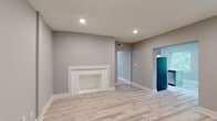 This updated apartment at 1207 E Armour Blvd in Kansas City, Missouri offers a thoughtfully renovated single-floor layout with contemporary finishes throughout. The living area is a welcoming focal point, featuring a classic white brick fireplace, recessed lighting, and light-toned luxury vinyl plank flooring that flows consistently through the entire unit. Neutral gray walls provide a clean, modern backdrop throughout the space.

The kitchen is well-appointed with white shaker-style cabinetry, bright white countertops, a white subway tile backsplash, and a full suite of stainless steel appliances including a refrigerator, range, and over-the-range microwave. Natural light filters in through a window, adding to the kitchen's airy feel.

Multiple bedrooms offer comfortable accommodations, each with light-filled windows fitted with blinds. The primary bedroom includes a ceiling fan with lighting and generous closet space with double doors. Additional bedrooms provide natural light and easy access to the hallway.

Both bathrooms are elegantly finished with marble-style tile surrounds in the tub and shower areas, updated vanities with white basin sinks, chrome fixtures, and coordinating flooring. One bathroom also features a natural light window. The overall ambiance of the unit is clean, modern, and move-in ready.