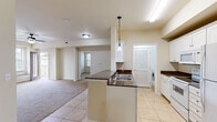 This single-floor residence offers a thoughtfully designed open-concept layout that seamlessly connects the kitchen, dining, and living areas. The kitchen is a functional centerpiece, featuring white cabinetry, dark granite countertops, a peninsula with a double-basin sink, pendant lighting, and a full suite of white appliances including a refrigerator, electric range, and built-in microwave. Light tile flooring runs throughout the kitchen and adjacent areas, while plush carpeting extends into the living room and all bedrooms. A dedicated in-unit laundry area is conveniently located just off the kitchen. The spacious living area flows naturally from the kitchen, offering an open and airy feel enhanced by neutral wall tones. The bedrooms are generously sized, each featuring ceiling fans with light fixtures, large windows with blinds that invite natural light, and soft carpeted floors. The bathrooms are finished with white vanity cabinetry, dark granite countertops, tile flooring, and tub-shower combinations with glass sliding doors. Throughout the space, a consistent warm, neutral color palette and clean white trim create a cohesive and inviting atmosphere suited for comfortable everyday living.