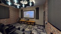 This dedicated home theater space is thoughtfully designed to deliver a premium cinematic experience. At the front of the room, a large framed projection screen dominates the wall, paired with a ceiling-mounted projector that ensures a sharp, immersive picture. Flanking the screen are vertical acoustic panels, which also line the textured stacked-stone feature walls on either side, contributing to excellent sound quality throughout the space.

Seating consists of multiple rows of plush black leather recliner chairs, each equipped with cup holders and generous armrests, arranged in a tiered layout to provide unobstructed sightlines from every seat. A mustard-yellow upholstered bench with built-in storage sits along the front wall, adding a warm contrast to the otherwise dark, sophisticated palette.

The ceiling is a standout architectural feature, adorned with angular black acoustic baffles and starburst-style pendant lights that lend a dramatic, modern flair. Underfoot, a bold geometric-patterned carpet in charcoal and grey tones ties the room together cohesively. Dark curtains line the rear wall, enhancing light control for an optimal viewing environment. The overall ambiance is sleek, polished, and purpose-built for an exceptional entertainment experience.